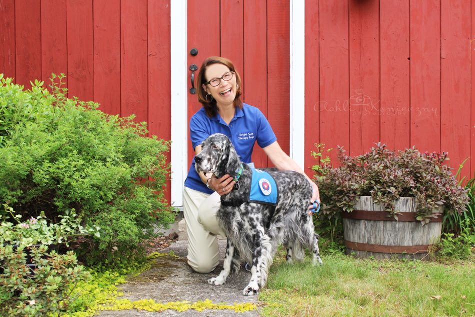 blue belton english setter lily wears blue dog vest and poses with handler wearing blue shirt.