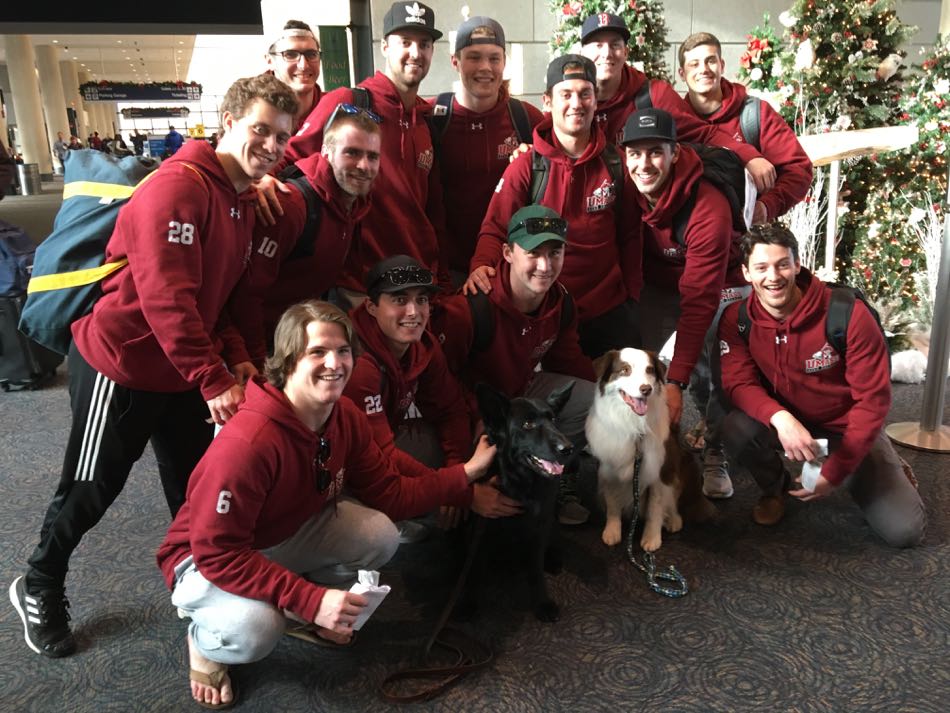 an athletic team of several young men have their photo taken with two therapy dogs.