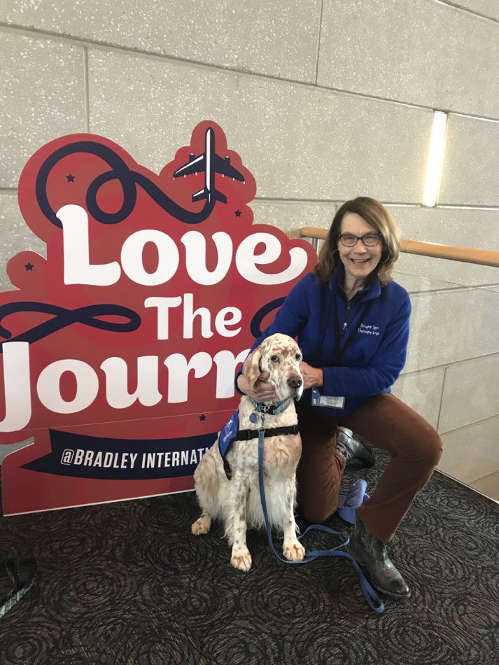 English Setter King and owner pose in front of a sign at the airport