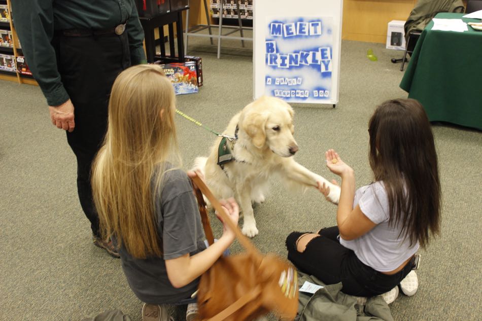 Golden Retriever offers his paw to two children sitting on floor next to him